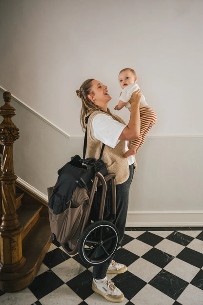 Mutter nutzt den Tragegurt zum freihändigen Tragen des Kinderwagens